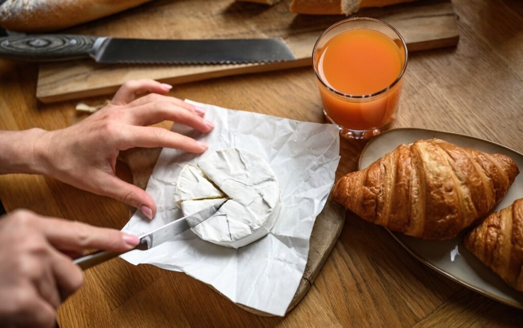 Une femme découpant du camembert pour le petit déjeuner