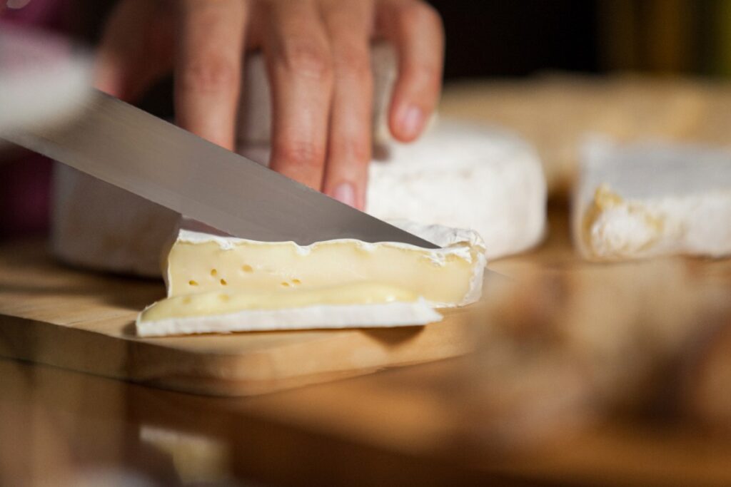 Une personne qui découpe du fromage camembert