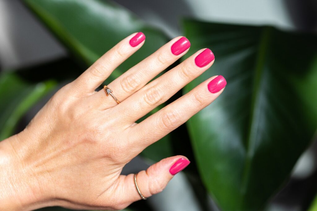 Une main d'une femme avec des ongles en rose fluo