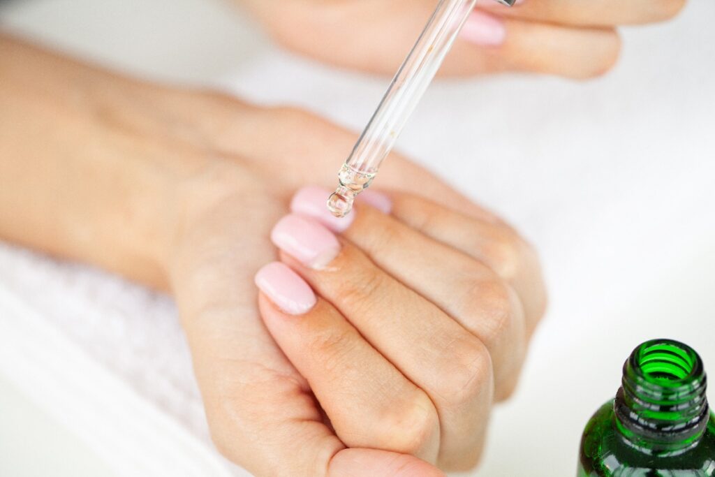 Une personne qui applique de l'huile ricin sur ses ongles