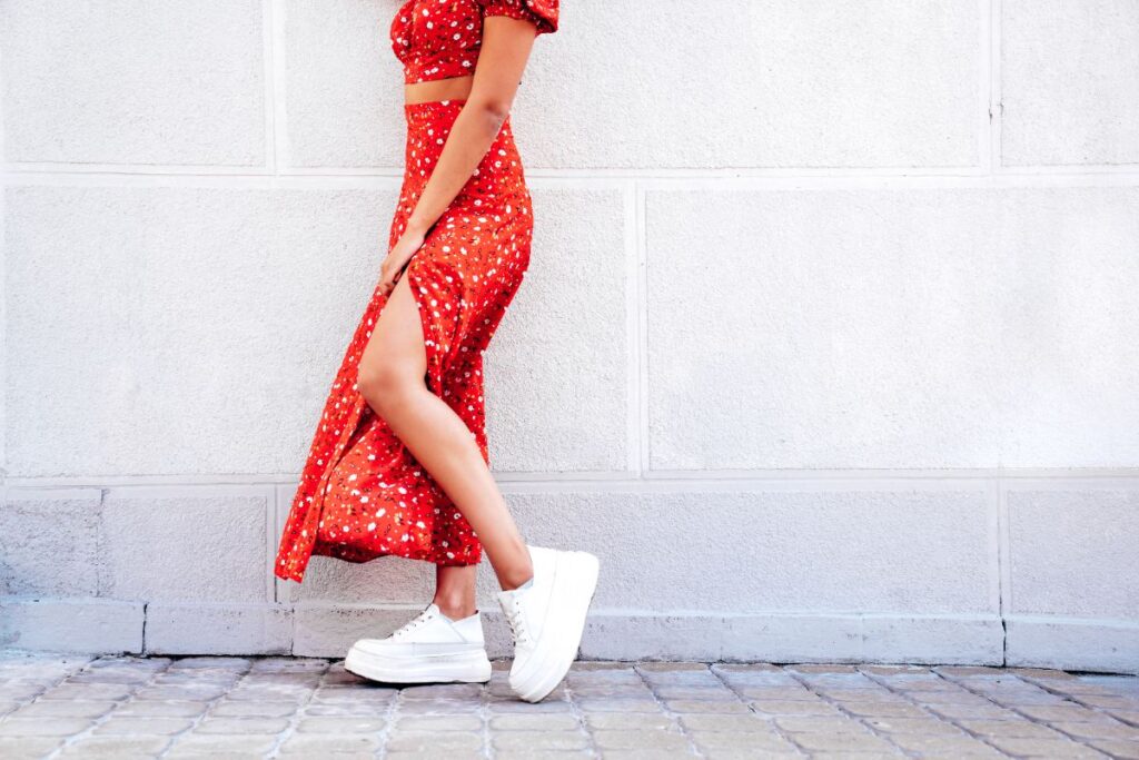Une femme qui porte une robe fleurie avec un basket blanc