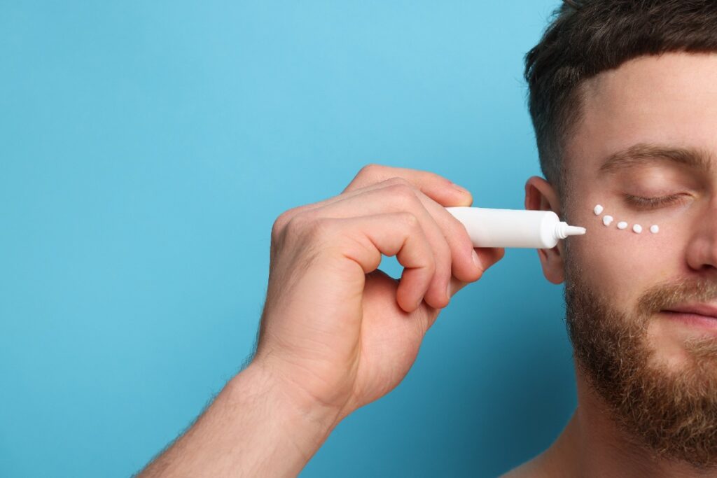 Un homme qui applique de la crème autour de ses yeux