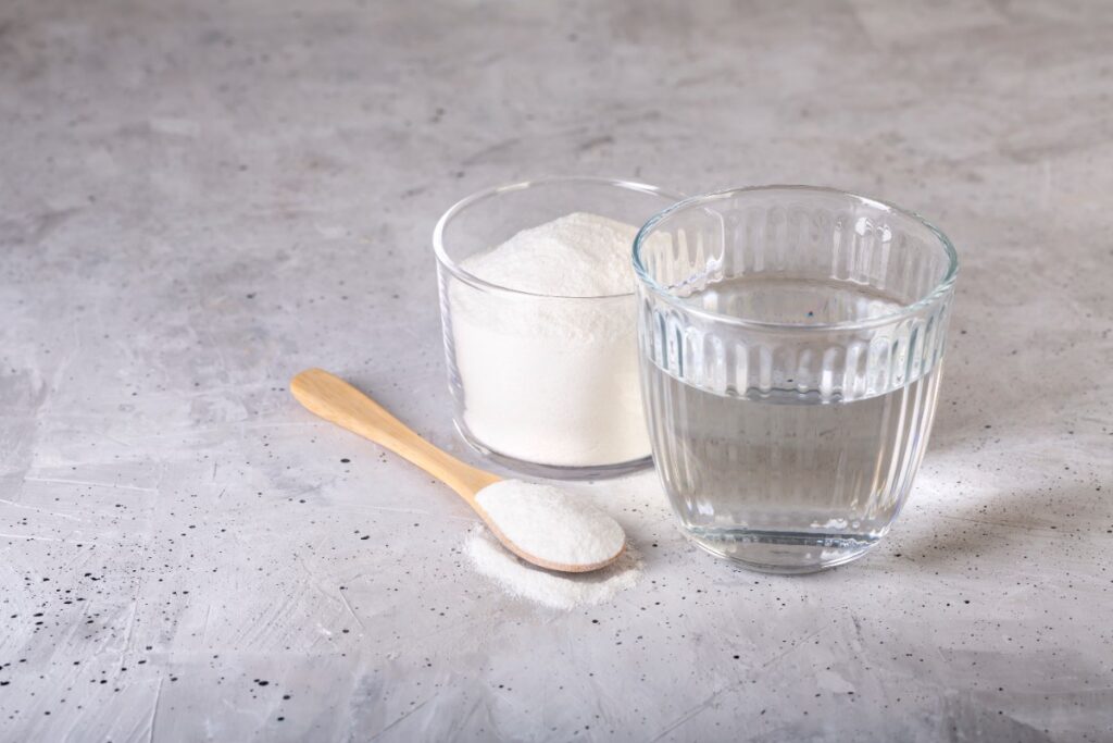 Un verre d'eau avec un verre et une cuillère remplies de bicarbonate de soude