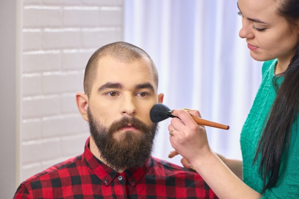 Une femme appliquant du maquillage sur le visage d'un homme