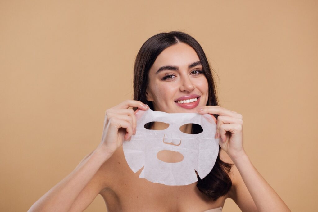 Une femme souriante tenant un masque facial