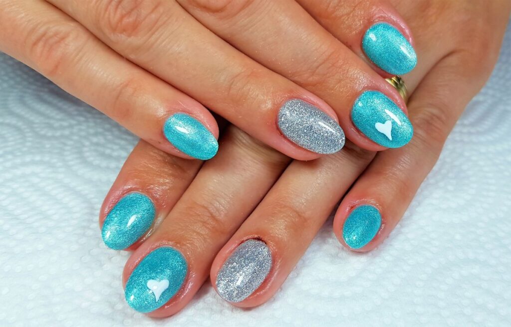 Mains avec du nail art scintillant turquoise et argent